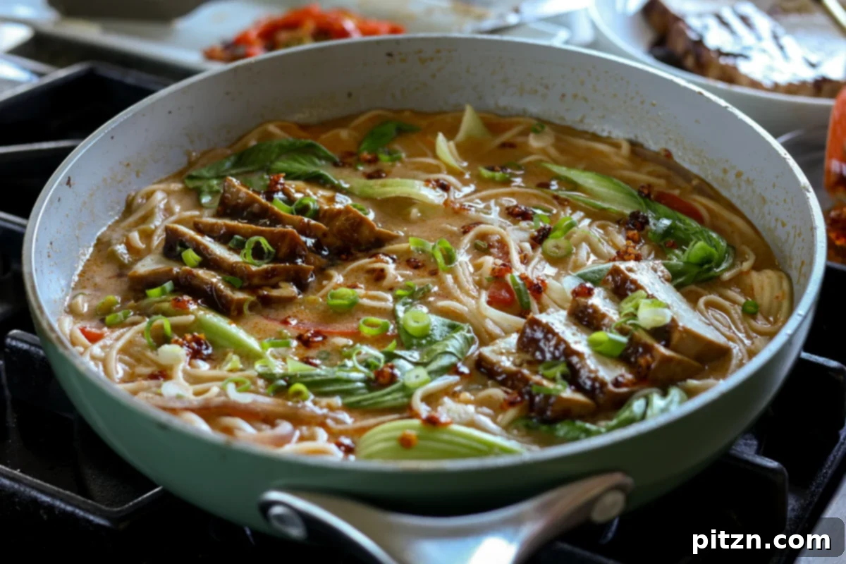 the finished creamy tahini ramen in a bowl, generously topped with teriyaki tofu, green onions, and chili crisp