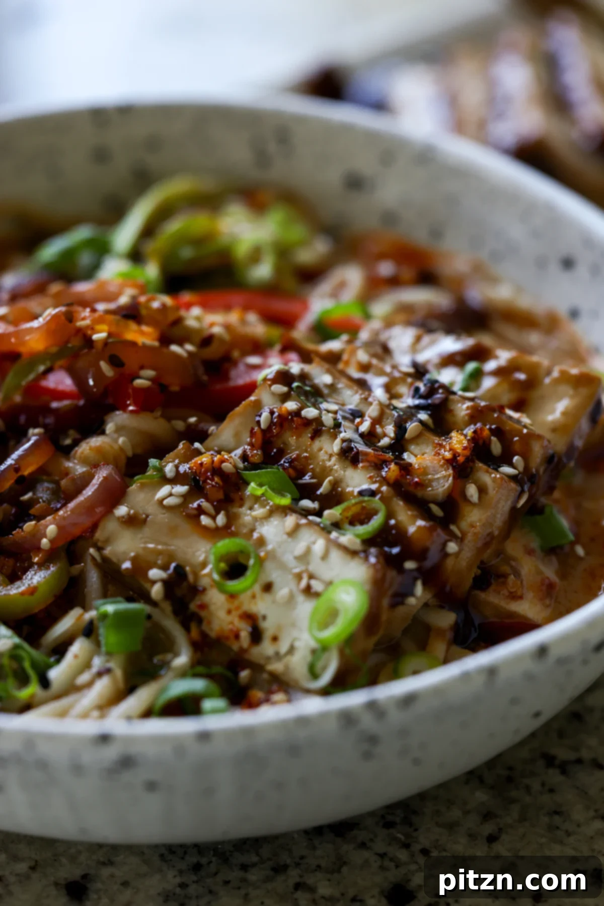 close-up of a bowl of creamy tahini ramen, showcasing the perfectly cooked noodles, rich broth, and glazed tofu slices
