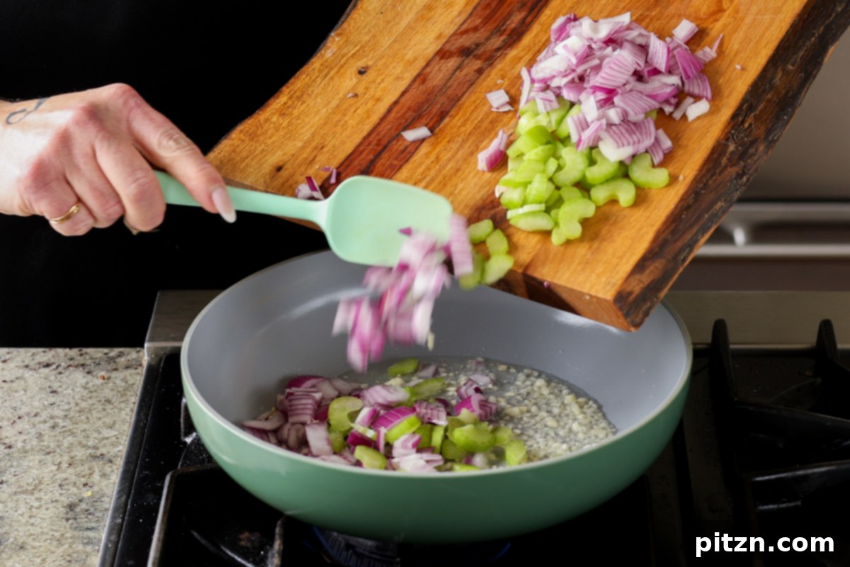 Adding chopped onions and celery to the skillet with garlic.