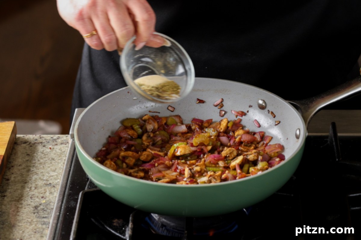 Adding various herbs and spices to the pot pie filling in the pan.