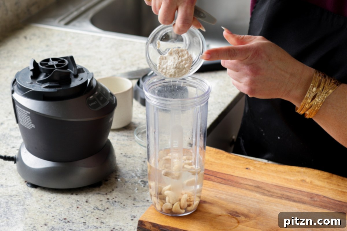 Ingredients for cashew cream being added to a blender.