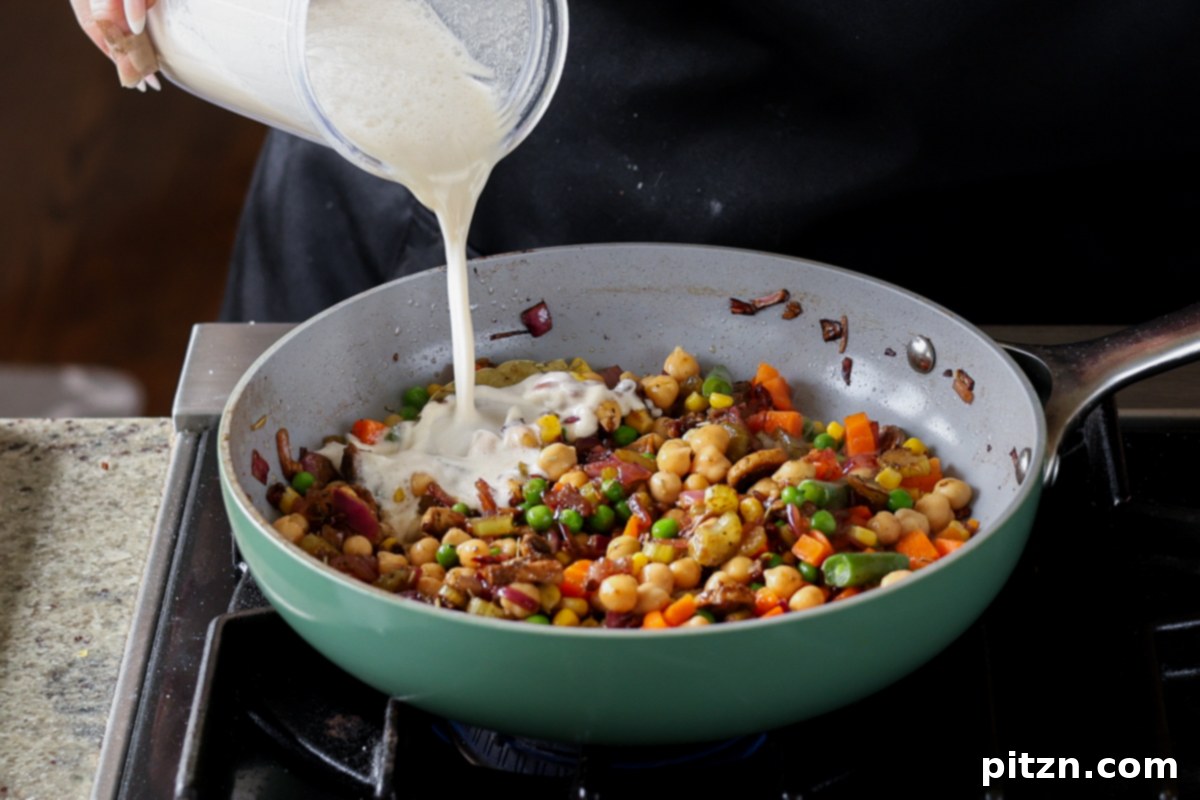 Adding the cashew cream to the pot pie filling in the pan.