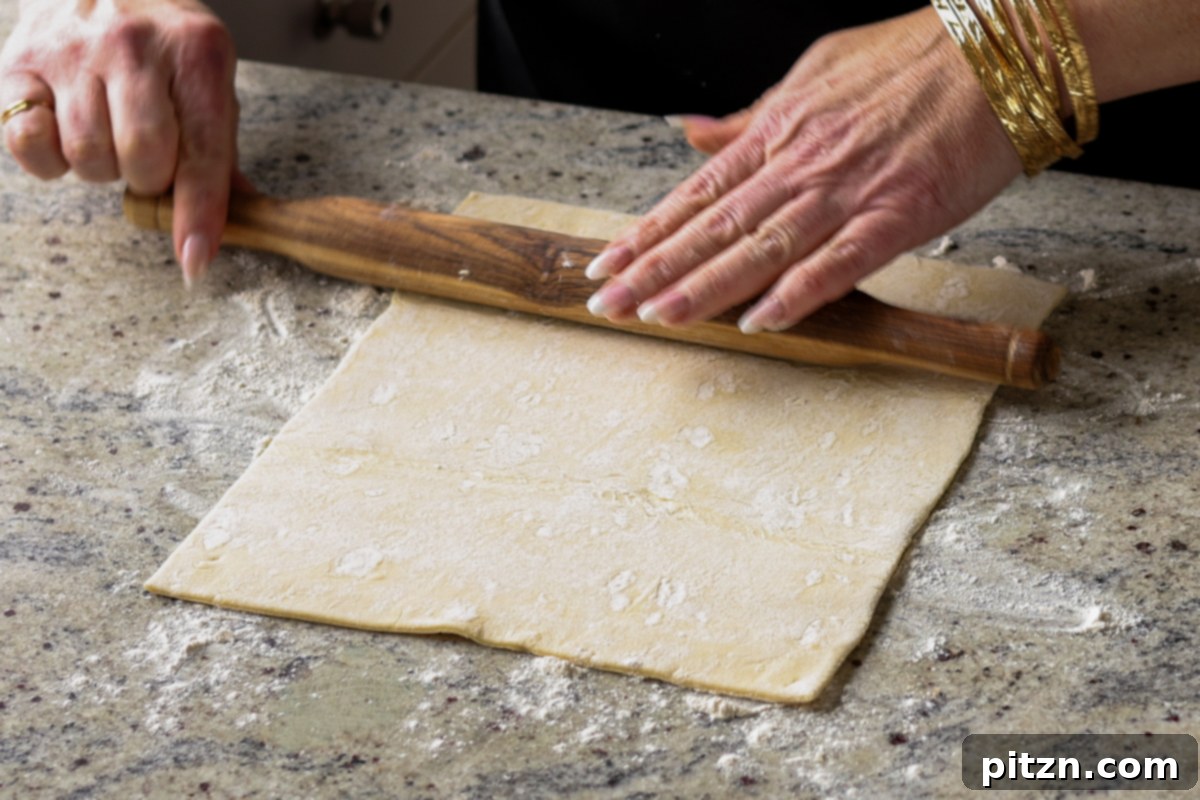 Rolling out the puff pastry sheet on a floured surface.
