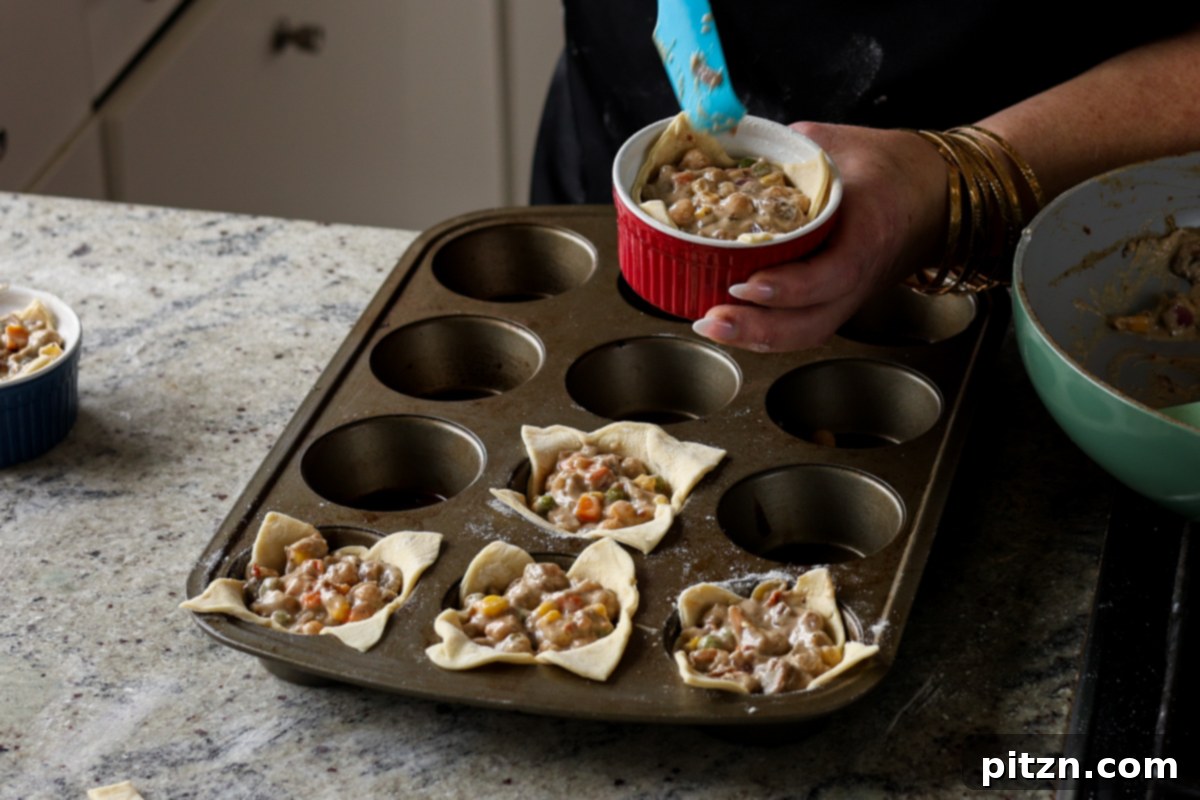 Filling puff pastry shells in ramekins with the pot pie mixture.