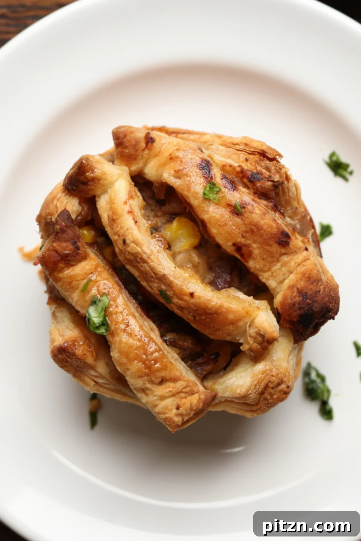A simple-crusted mini pot pie on a white plate, ready to be enjoyed.