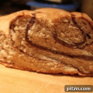 Decadent Chocolate Swirl Bread 2 A loaf of chocolate swirl bread cut in half on a wooden cutting board, revealing the beautiful chocolate patterns within.
