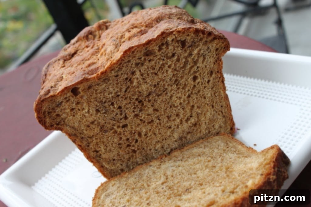 Artisan Molasses Raisin Oat Flax Loaf 3 Close-up of a rustic, homemade bread with a craggy crust, cooling on a wire rack, hinting at its robust, hearty interior. Vegan-friendly whole wheat bread.