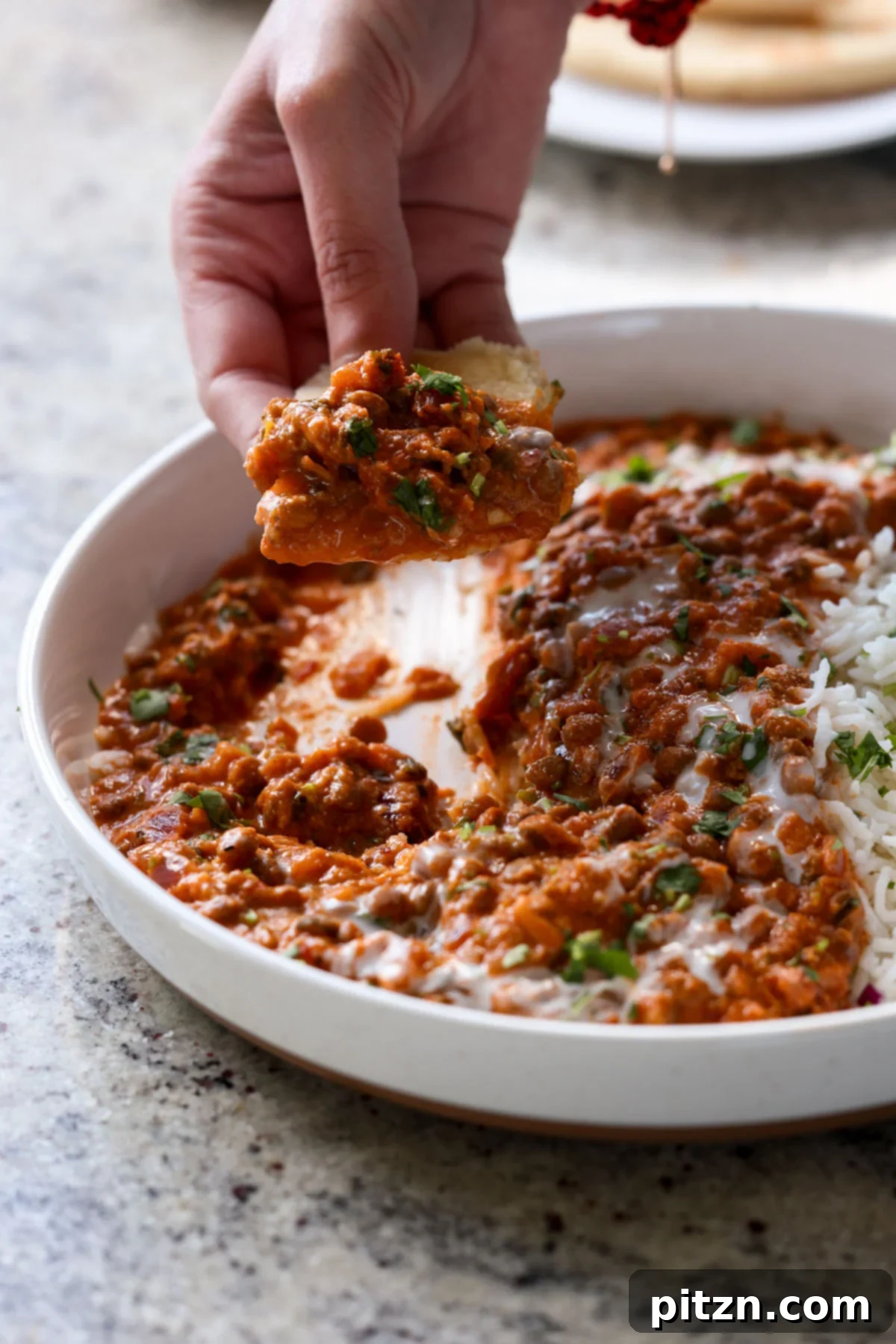South Indian Soulmate Lentils 5 Hand scooping up South Indian Marry Me Lentils with a piece of flatbread, ready to eat.