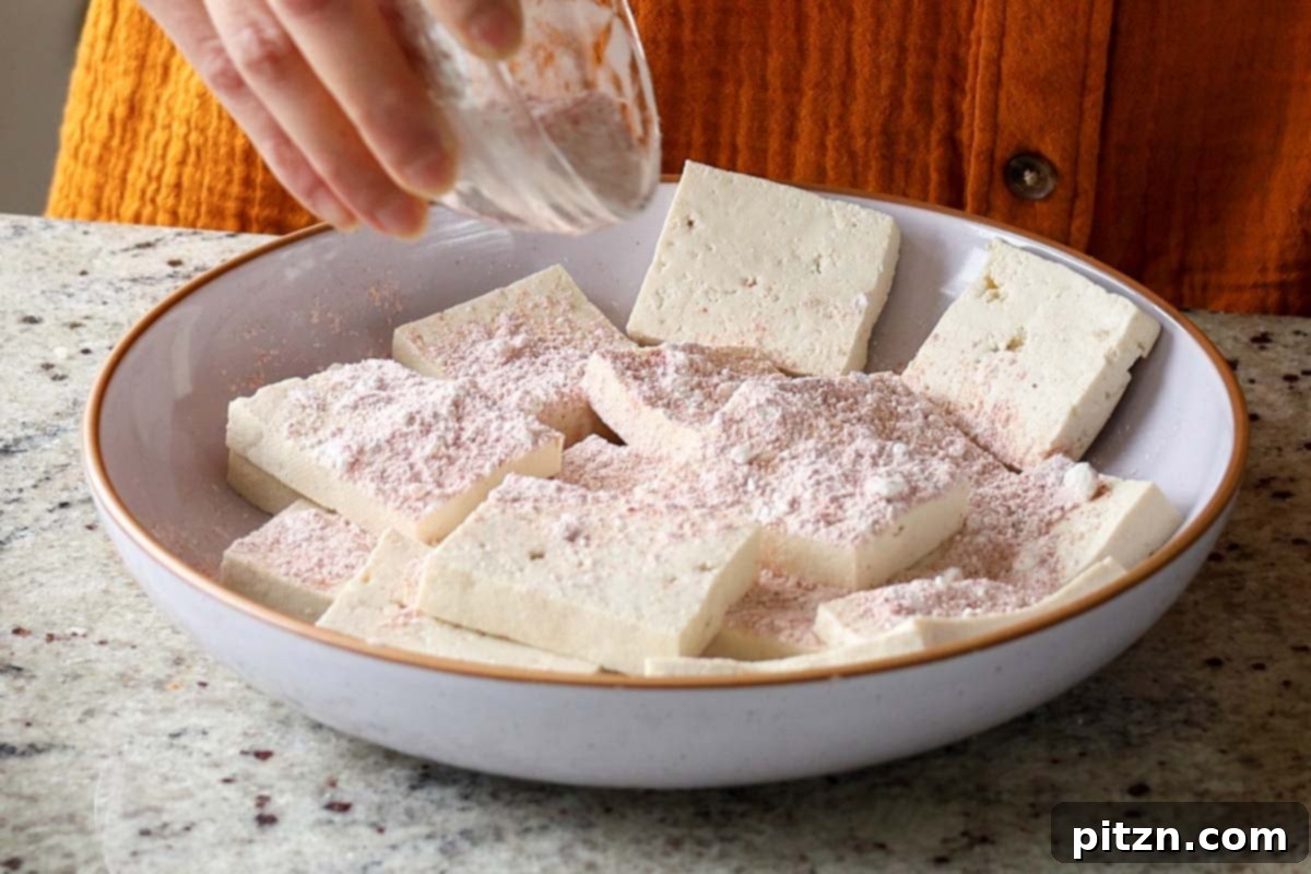 Adding individual tofu slices to the dry spice mix for coating