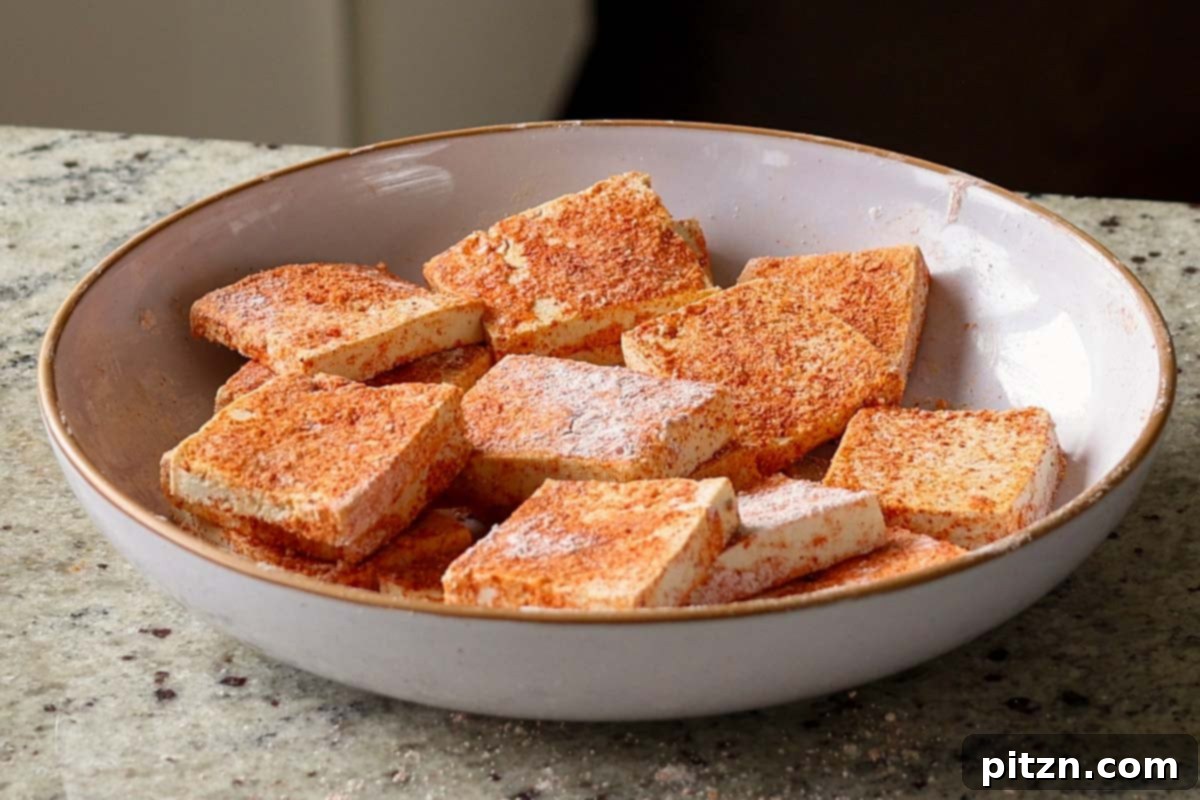 Close-up of tofu pieces fully coated in the red spice and cornstarch mixture