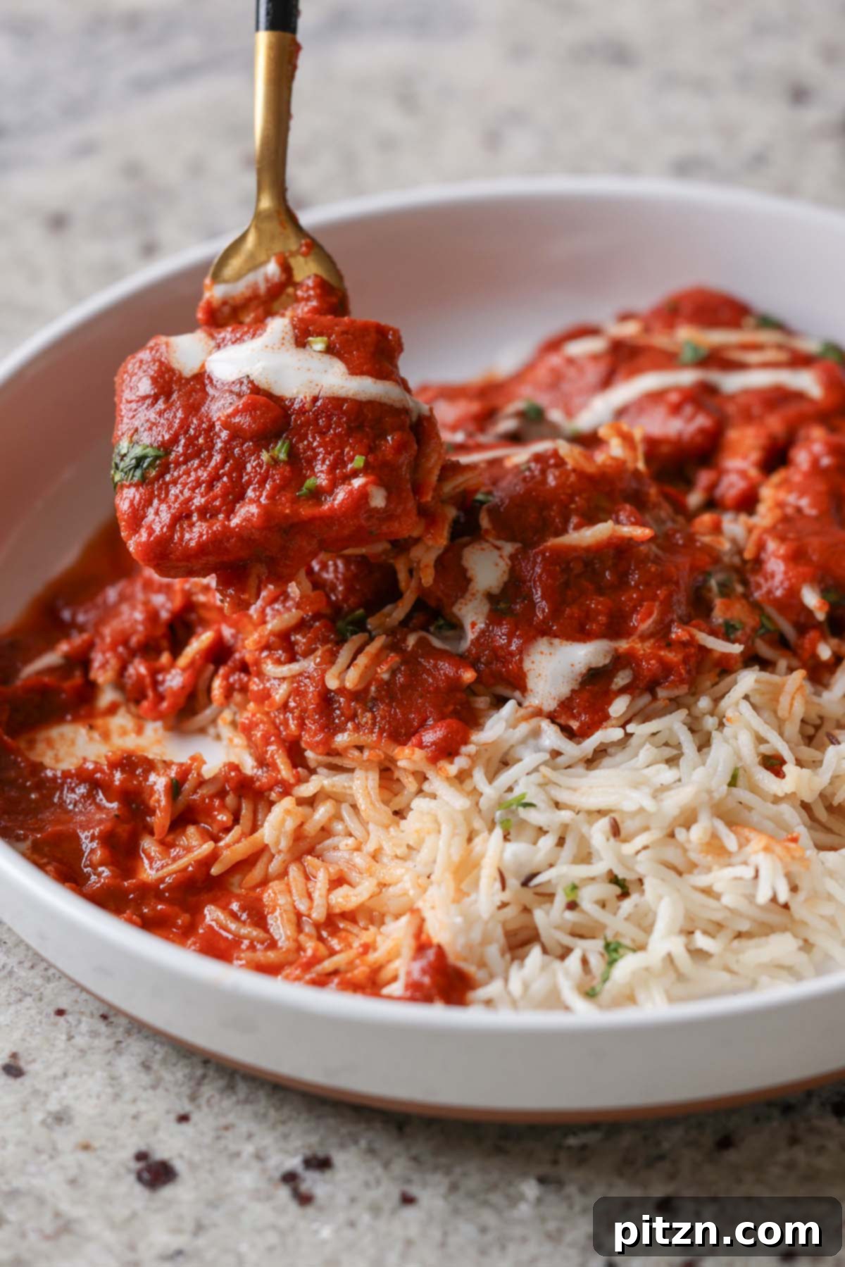 A fork taking a bite of Vegan Kashmiri Lal Tofu with rice, garnished with non-dairy yogurt