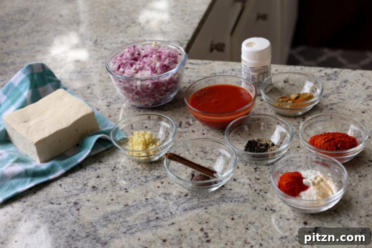 Various ingredients for Kashmiri Lal Tofu laid out in bowls on a kitchen counter, showcasing fresh and dried spices.