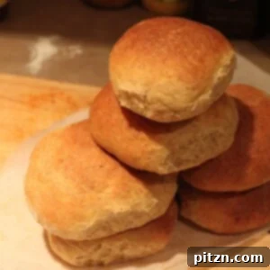A stack of golden-brown vegan orange buns, garnished with fresh orange slices, on a rustic wooden board.