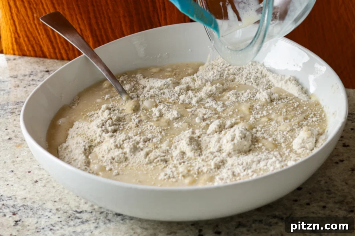 Pistachio Perfection Trio 15 The wet ingredients being carefully poured into the bowl of dry ingredients for the pistachio cake batter.
