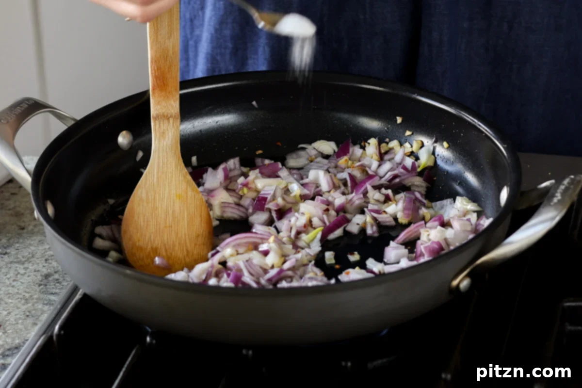 Adding chopped onion to the pan with garlic and red pepper flakes.