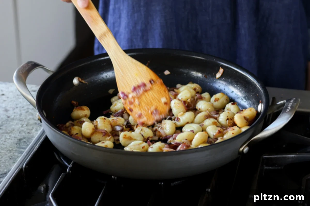Crisped-up gnocchi cooking in the pan after initial searing.