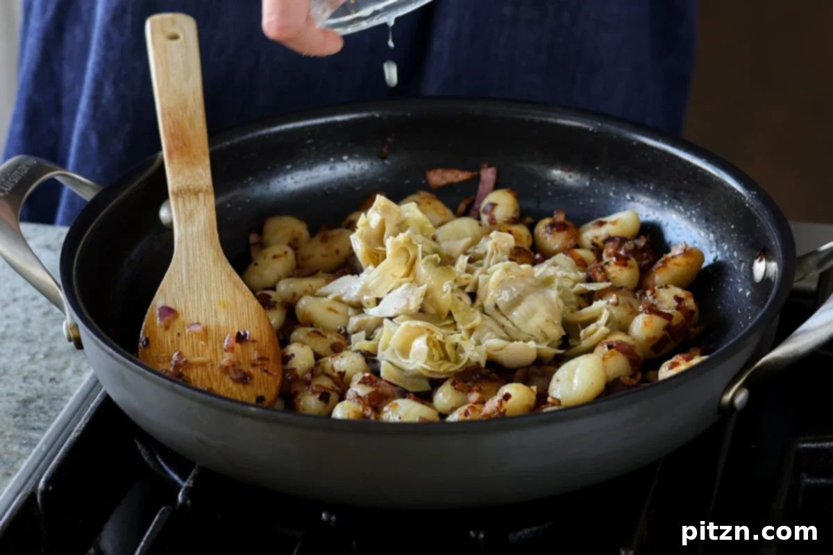 Adding chopped marinated artichoke hearts to the pan.