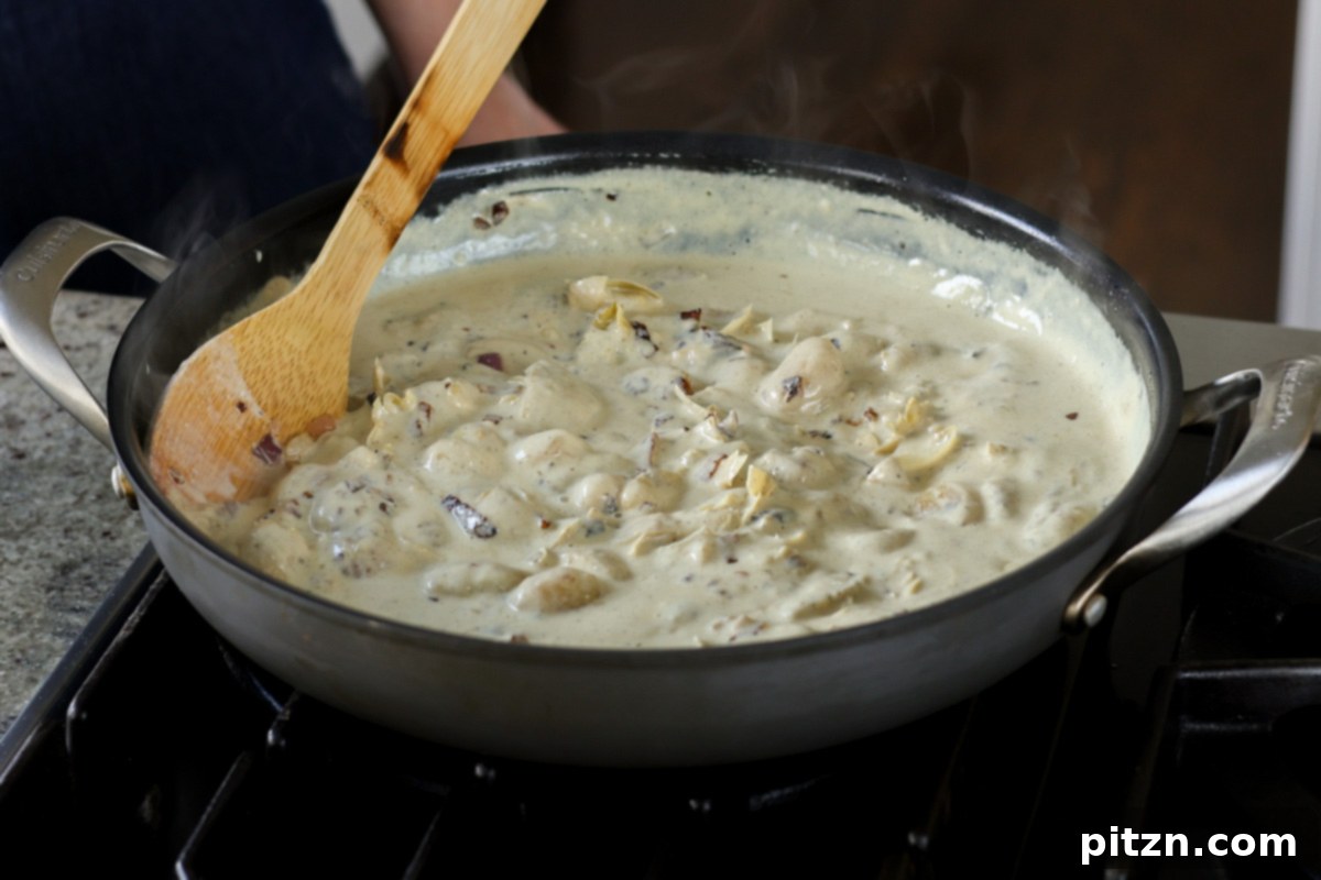 Gnocchi simmering in the rich, creamy spinach artichoke sauce.