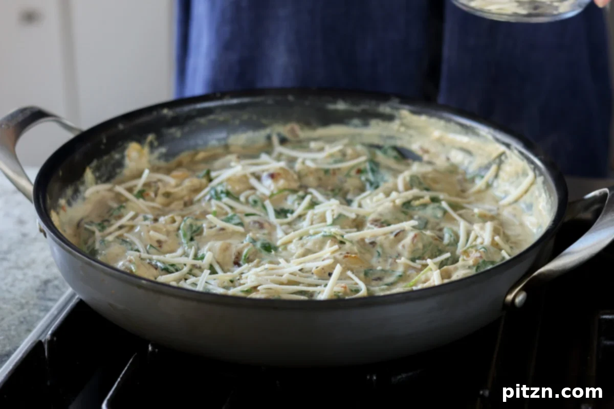 Sprinkling vegan mozzarella cheese over the spinach artichoke gnocchi in the pan.