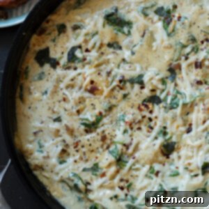 Close-up of spinach artichoke gnocchi in the pan, showing rich sauce and tender gnocchi.