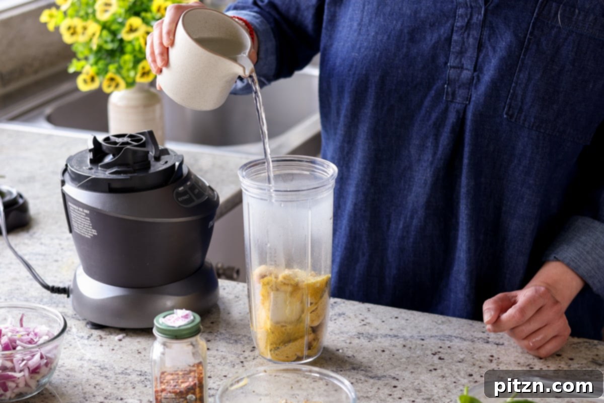 Pouring cream sauce ingredients into a blender.