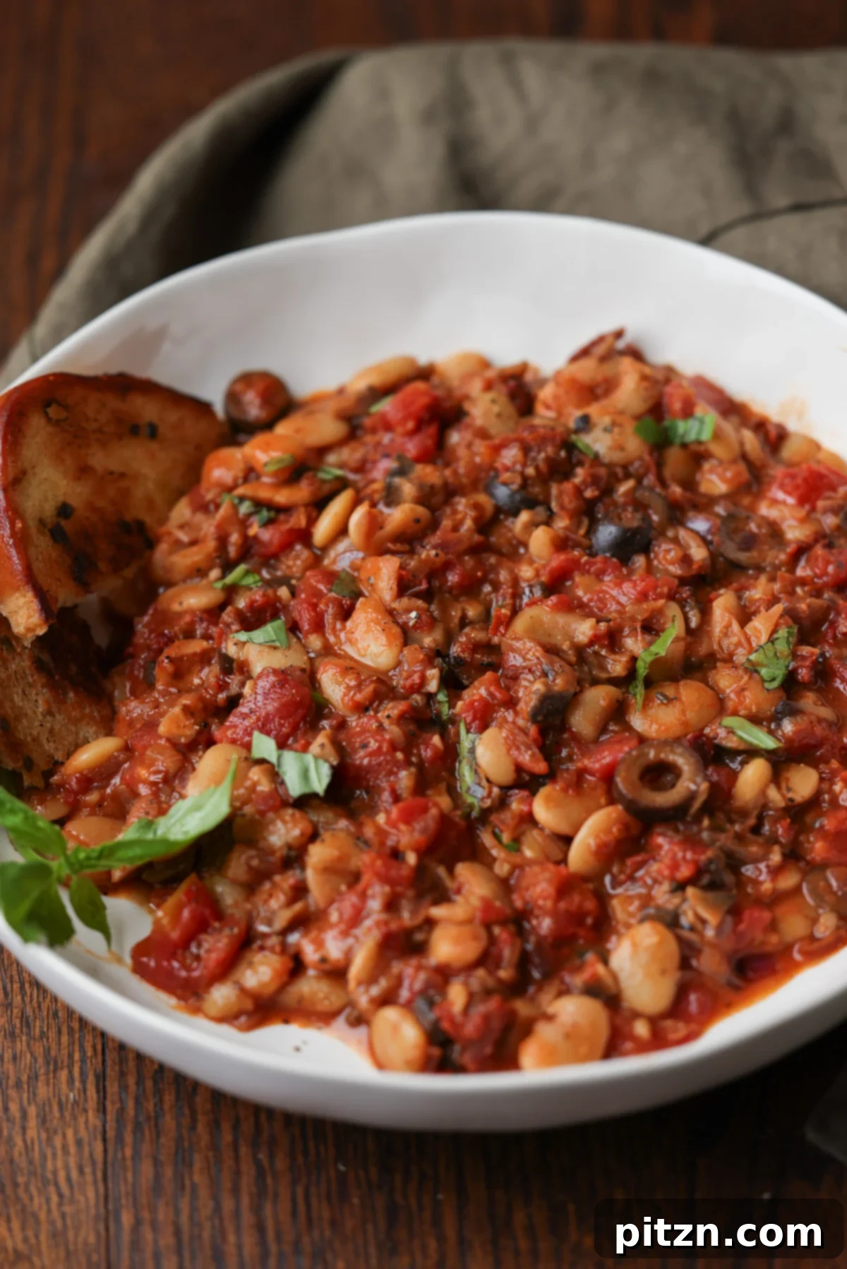 Zesty Mediterranean Butter Beans 2 puttanesca beans on a plate with garlic bread