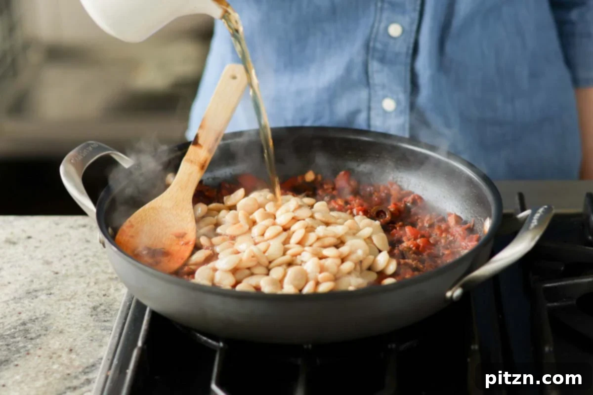 Zesty Mediterranean Butter Beans 14 adding butter beans and water to the pan