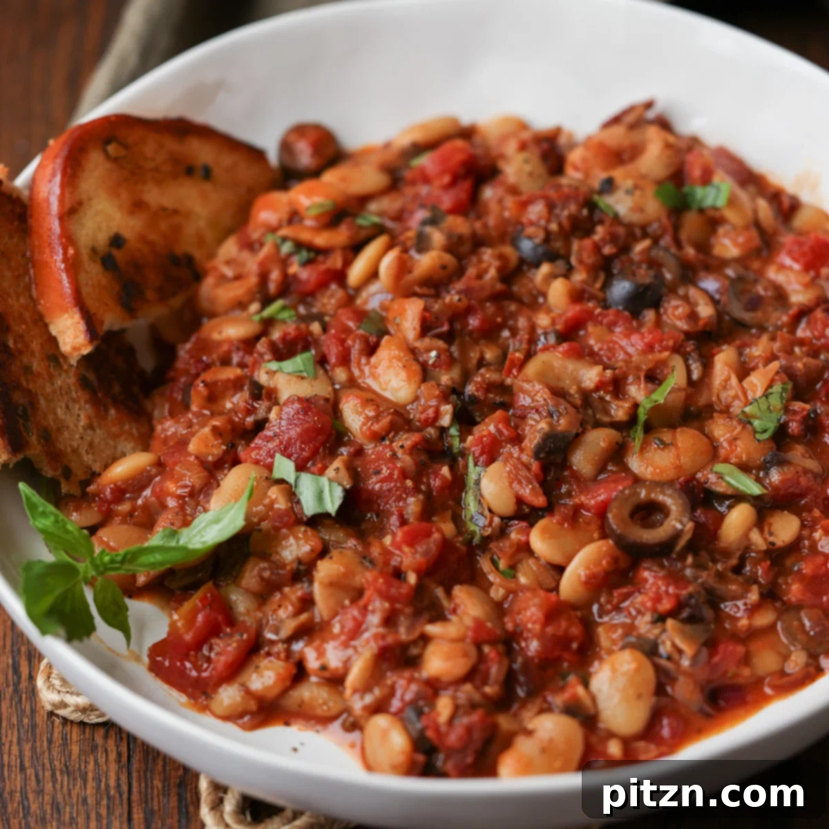 Zesty Mediterranean Butter Beans 18 puttanesca beans on a plate with garlic bread