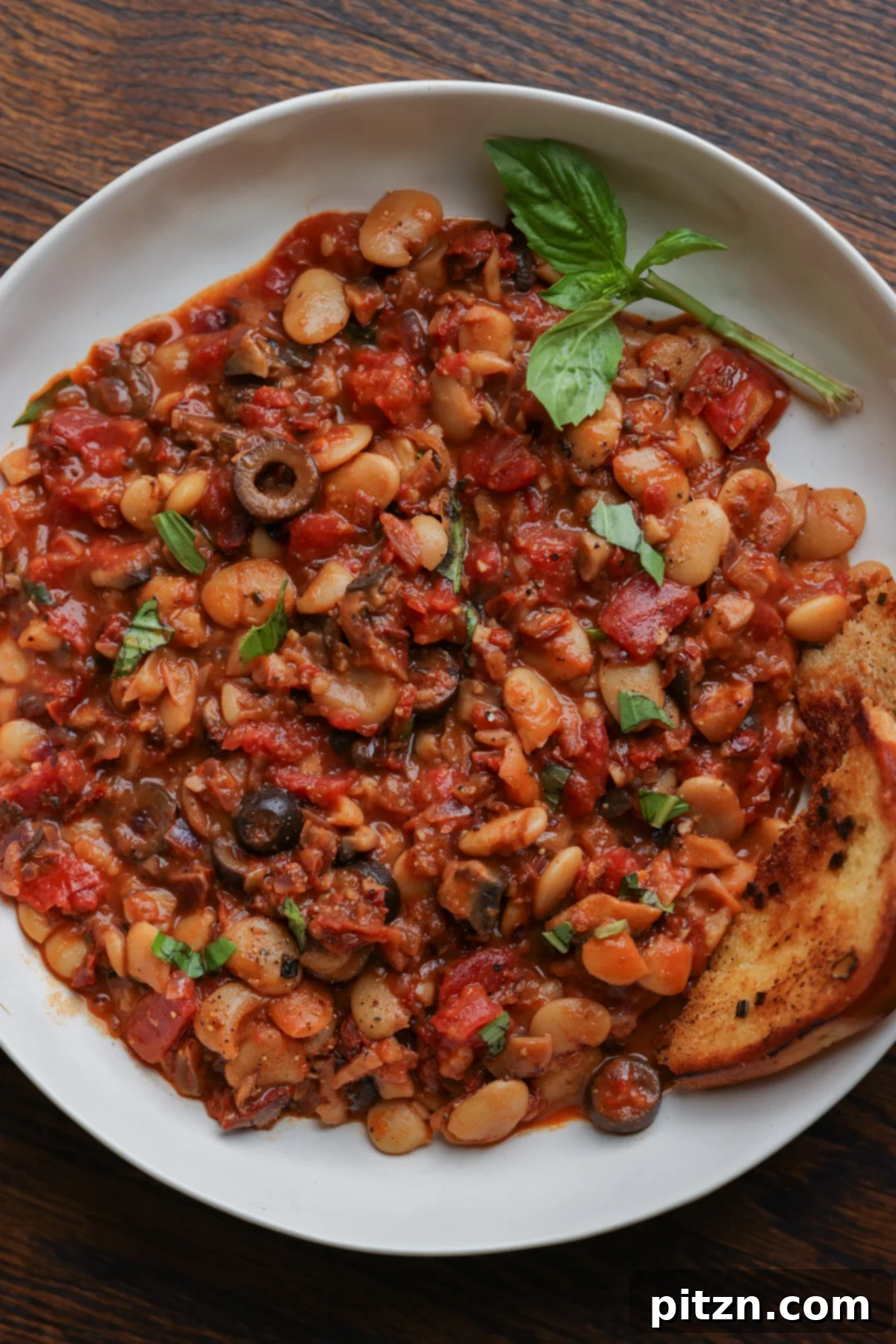 Zesty Mediterranean Butter Beans 4 close-up of puttanesca beans on a plate with garlic bread