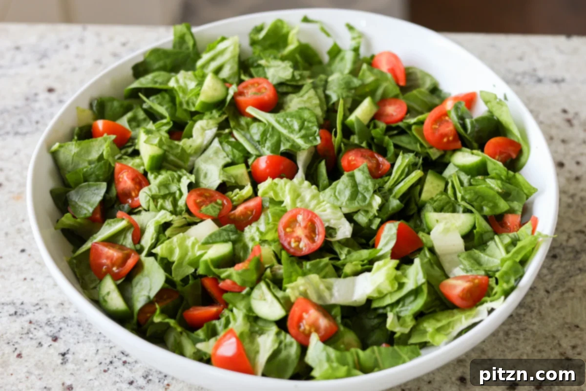 Sun-Drenched Spinach Salad with Zesty Olive-Chickpea Crunch 11 Chopped vegetables lightly tossed together in a salad bowl, forming a colorful and fresh base for the salad.