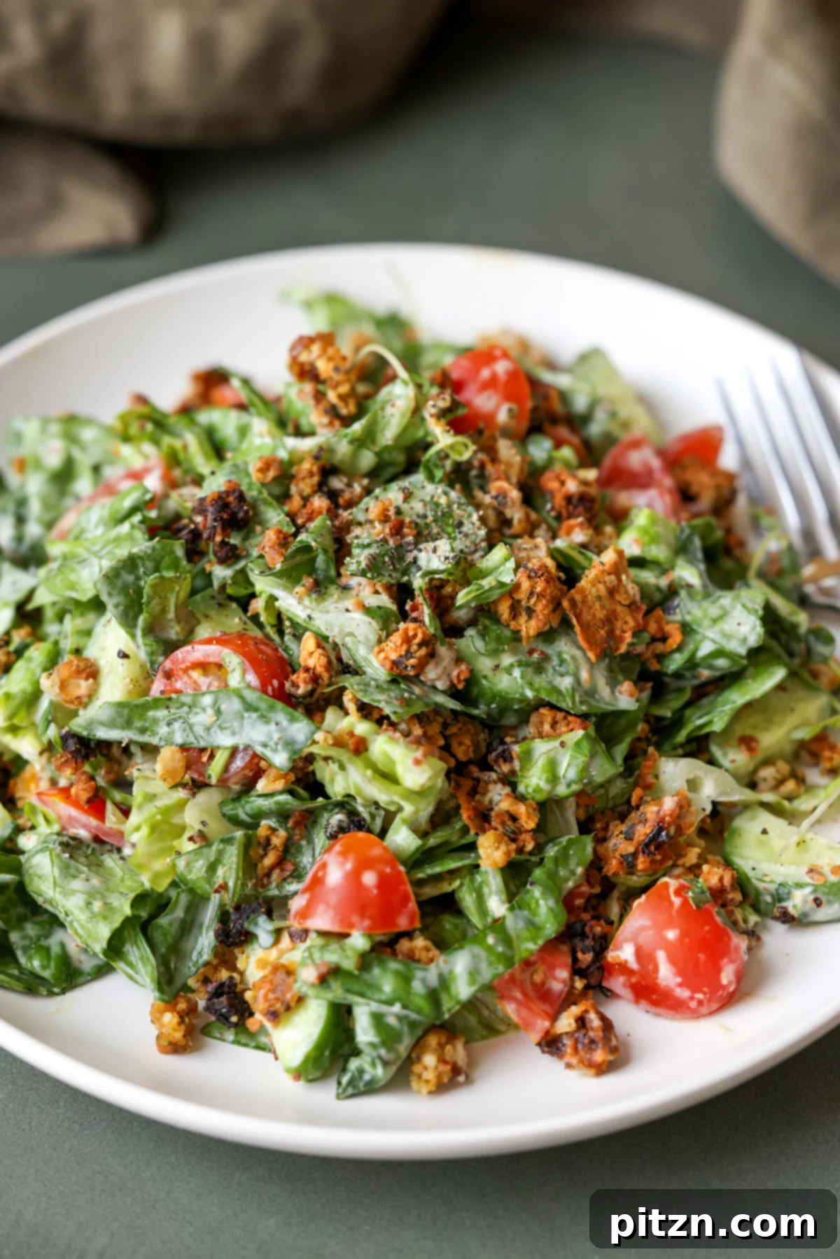 Sun-Drenched Spinach Salad with Zesty Olive-Chickpea Crunch 15 A close-up shot of a single serving of summer spinach salad with chickpea olive crumbles on a plate, with a fork poised to take a bite.