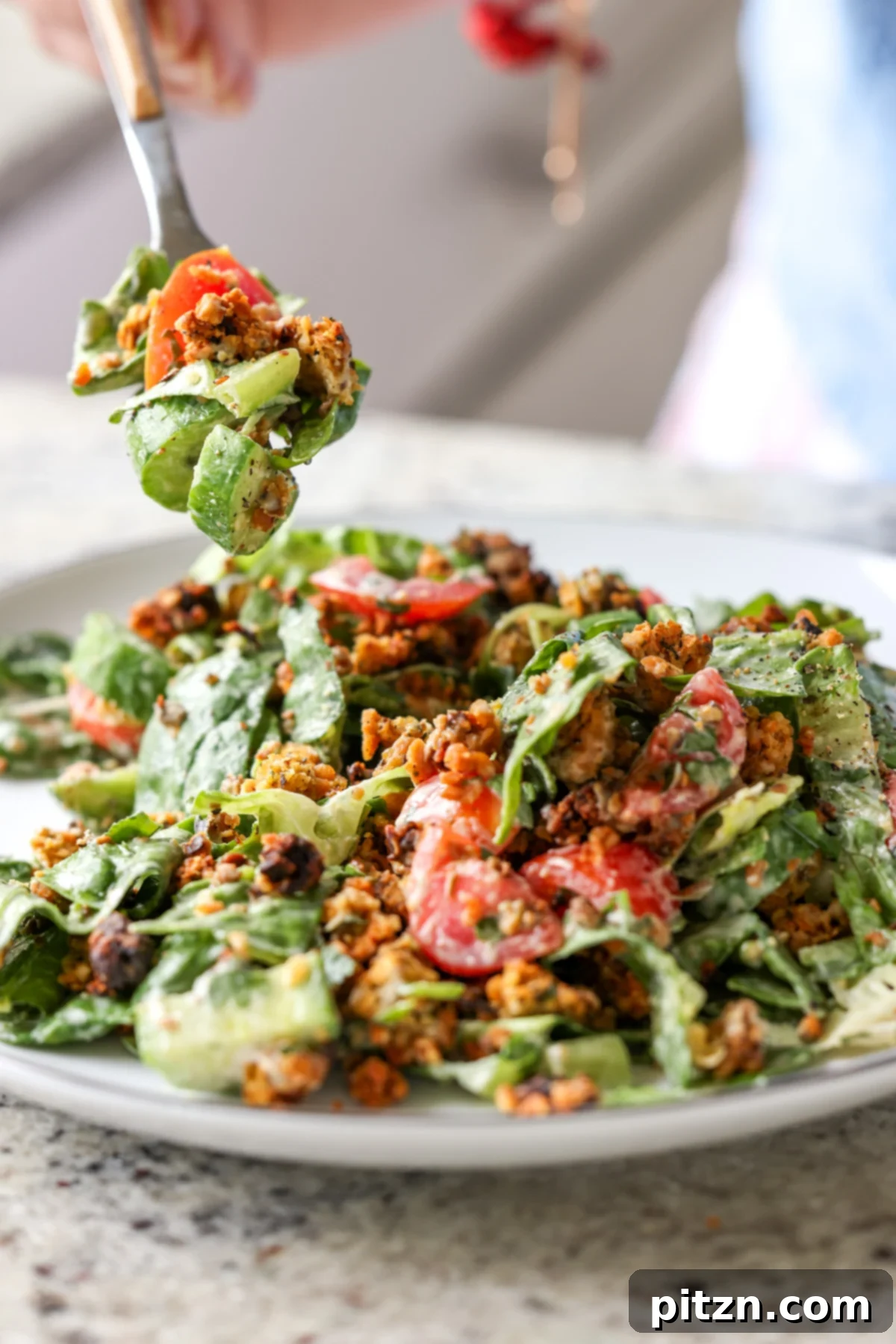 Sun-Drenched Spinach Salad with Zesty Olive-Chickpea Crunch 3 Fork taking a bite of a hearty summer spinach salad with crispy chickpea olive crumbles, showcasing its delightful textures.