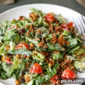 summer spinach salad with chickpea olive crumbles on a plate with a fork