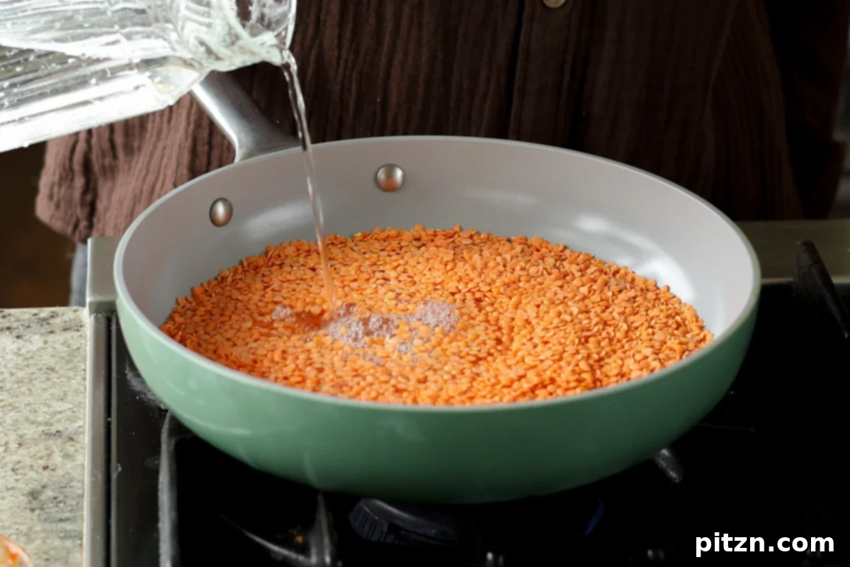 Lentil Protein World Tour Mix 10 Adding red lentils and water to a saucepan for cooking.