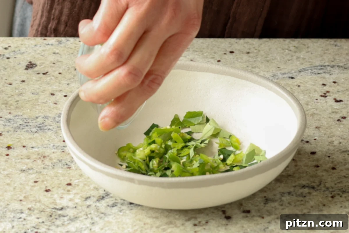 Lentil Protein World Tour Mix 14 Adding chopped green chilis and curry leaves to a small bowl for tempering.