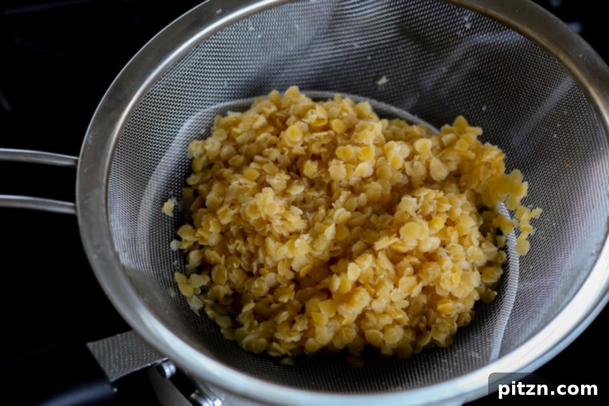 Drained, cooked red lentils in a bowl, showing their distinct orange hue