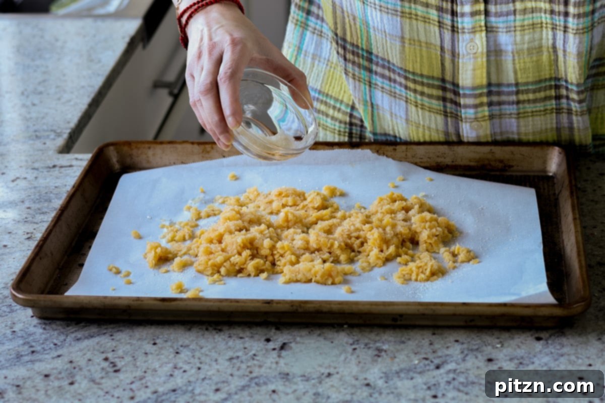 Adding perfectly drained red lentils onto a parchment-lined baking pan
