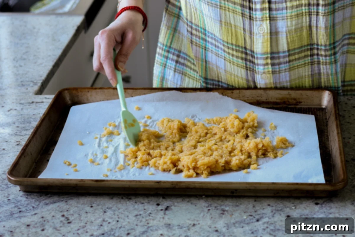Stirring red lentils with sugar on a baking pan for even coating