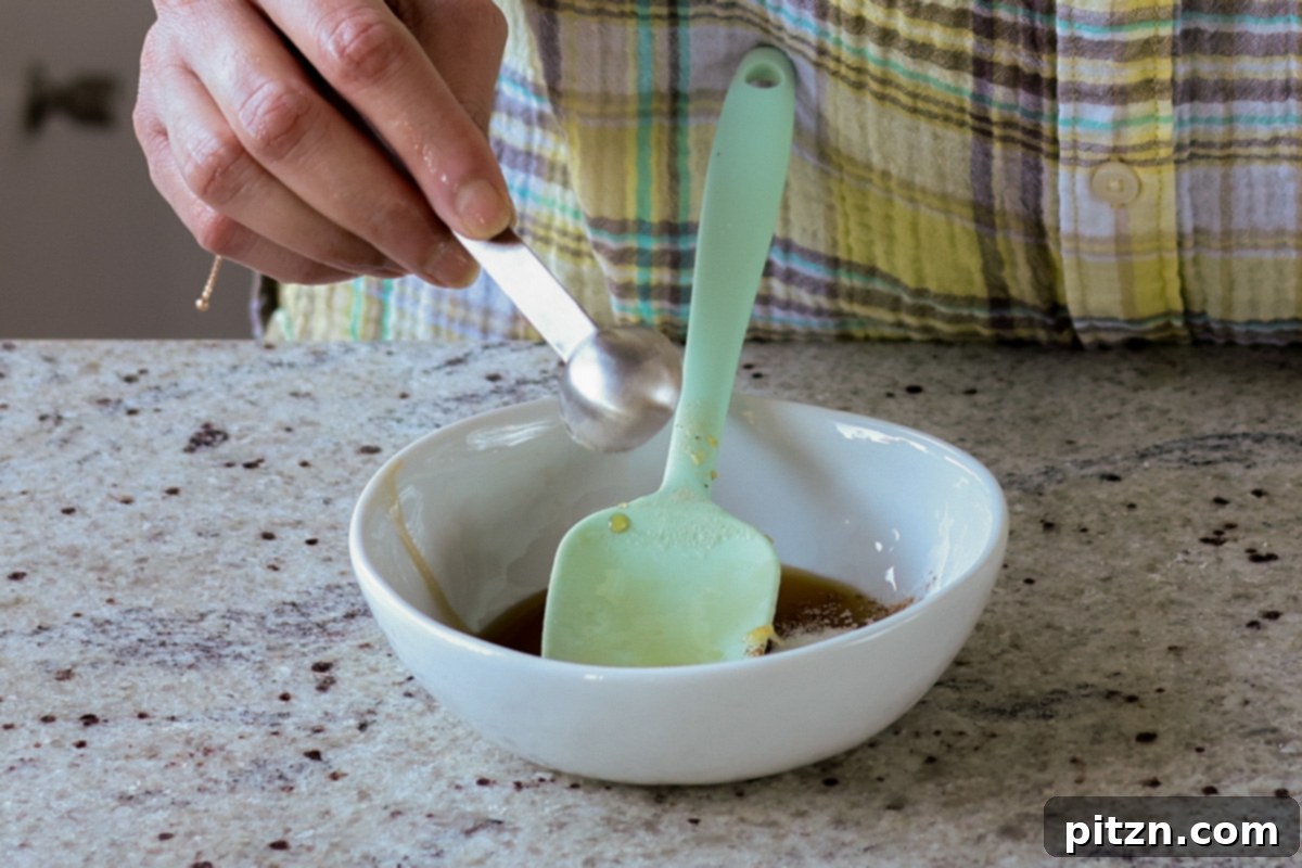 A bowl of maple syrup, cinnamon, vanilla, and oil being mixed for the granola