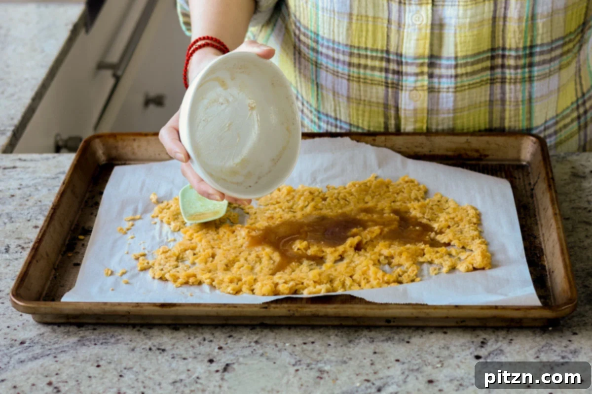 Pouring the maple syrup mixture over the partially baked red lentils on a pan