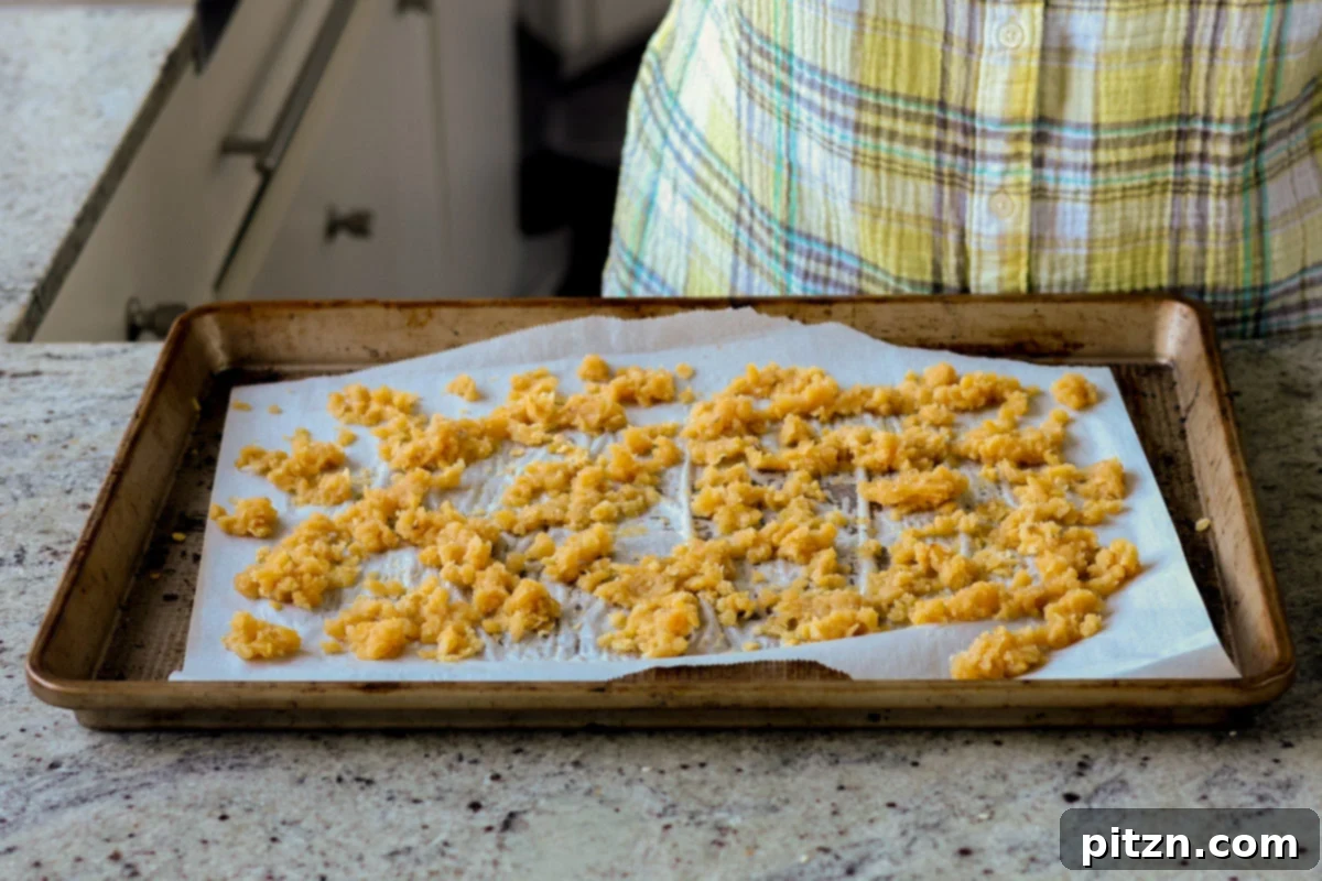 Red lentil granola spread out on the baking pan, before the final bake with mix-ins