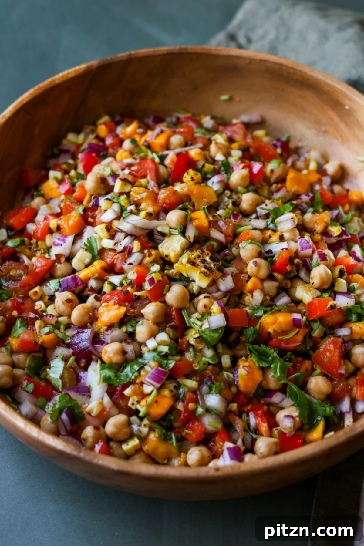 Tropical Chickpea & Mango Salad with Spiced Lime-Pepper Drizzle 2 A vibrant bowl of Mango Chickpea Salad, featuring golden chickpeas, diced mango, red bell pepper, corn kernels, and fresh cilantro, dressed in a light sauce, ready to be served.