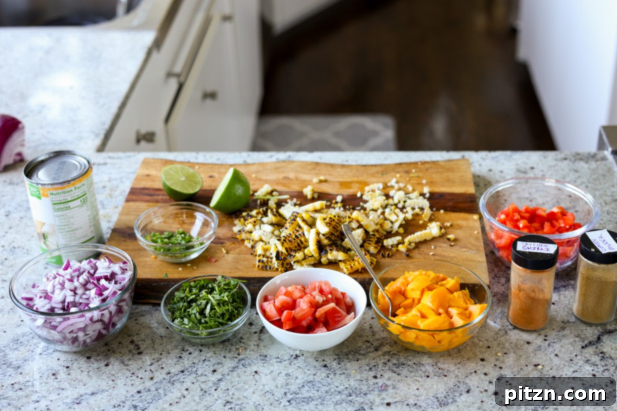 Tropical Chickpea & Mango Salad with Spiced Lime-Pepper Drizzle 10 Various chopped ingredients for Mango Chickpea Salad, including chickpeas, diced mango, red bell pepper, corn, and cilantro, arranged on a cutting board after preparation.
