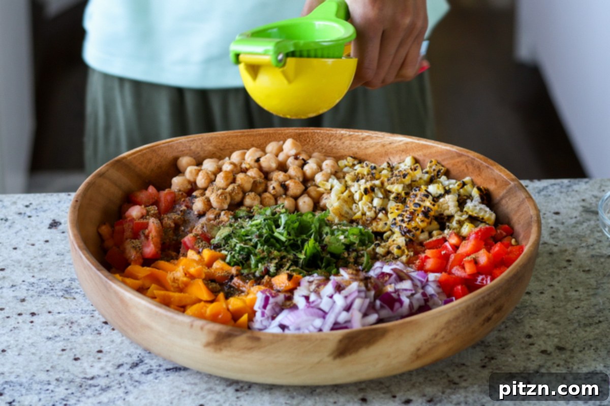 Tropical Chickpea & Mango Salad with Spiced Lime-Pepper Drizzle 15 A hand squeezing fresh lime juice over the ingredients in the large bowl of Mango Chickpea Salad.