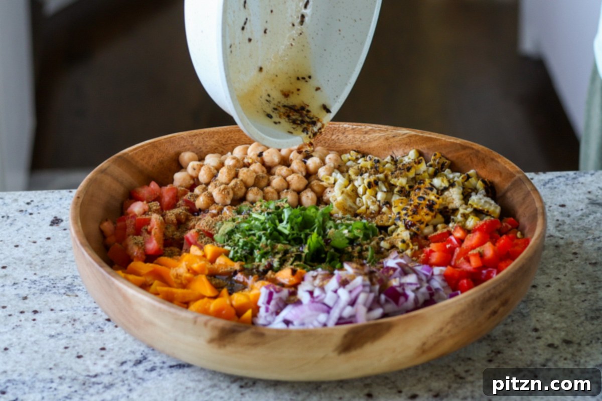 Tropical Chickpea & Mango Salad with Spiced Lime-Pepper Drizzle 16 A hand pouring the warm spiced oil over the mixed ingredients in the Mango Chickpea Salad bowl.