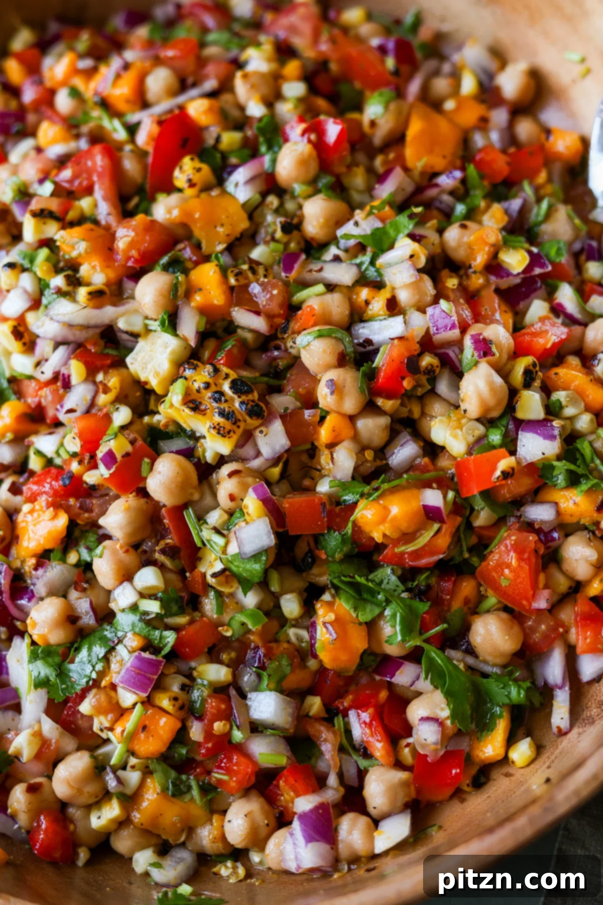 Tropical Chickpea & Mango Salad with Spiced Lime-Pepper Drizzle 4 A close-up view of Mango Chickpea Salad in a serving bowl, highlighting the texture and vibrant colors of the ingredients, including whole chickpeas, diced mango, and roasted corn.