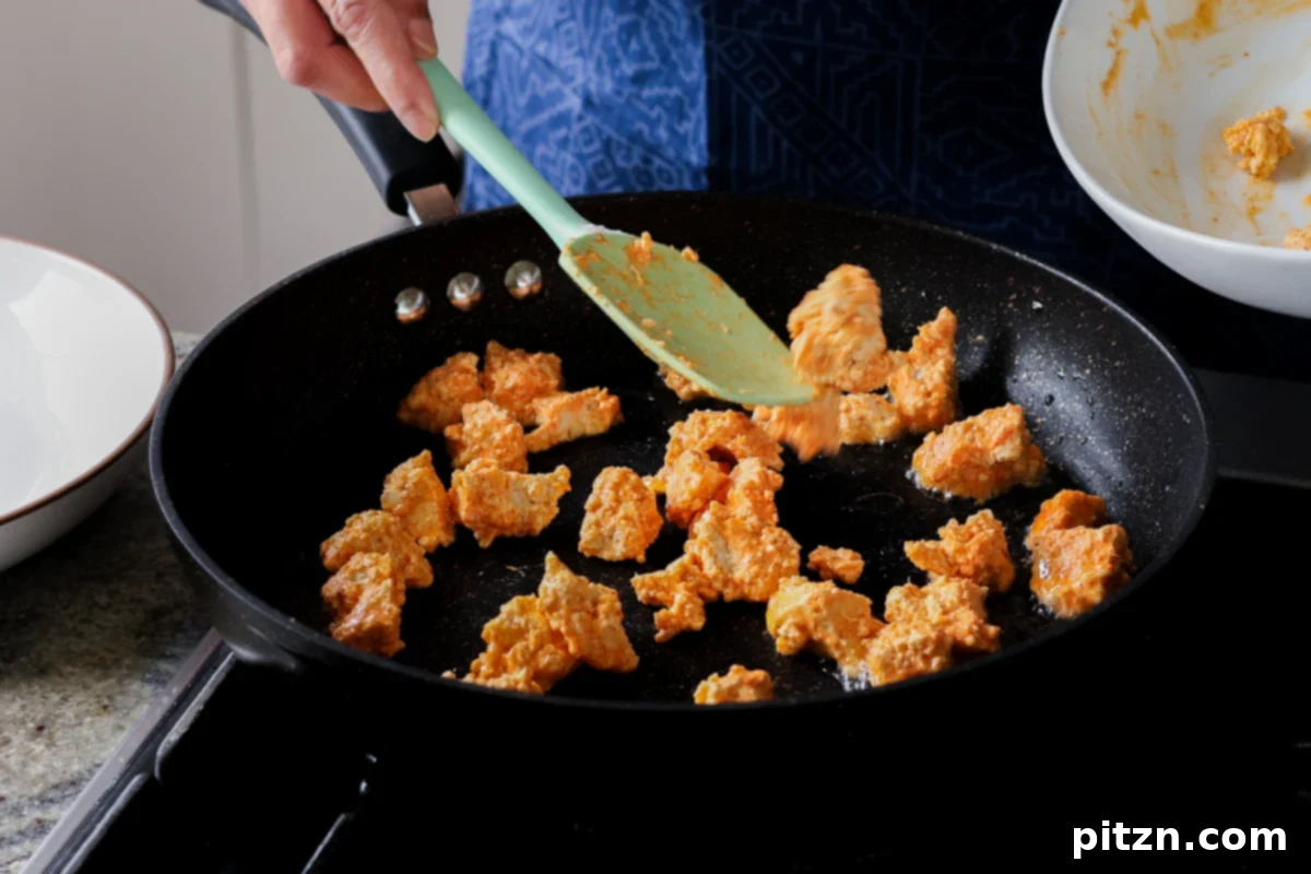 Crispy Vegan 555 Chicken Bites 17 Coated tofu pieces being added to a hot pan for pan-frying.