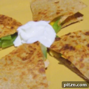 A grilled veggie quesadilla cut into quarters with vegan sour cream in the center, on a yellow plate.