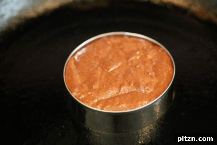 Stovetop vegan chocolate cake layer cooking in a cookie cutter