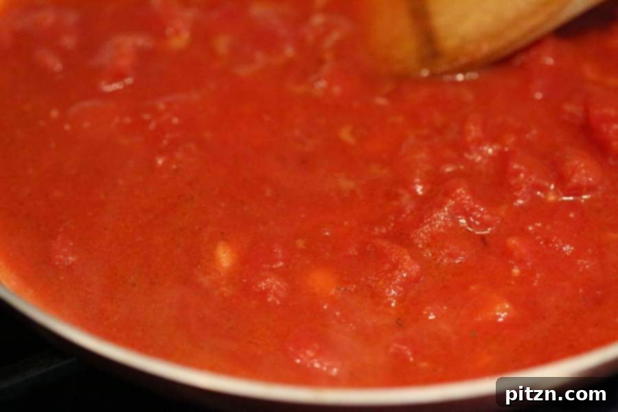 Savory Garlic Tomato Sauce over Vegan Chickpea Pasta 8 Simmering the garlic tomato sauce in a skillet, showcasing the rich color and texture before serving with chickpea noodles.
